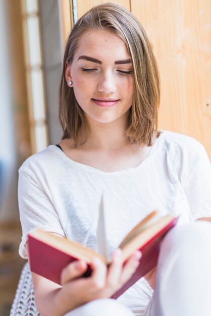 Libro di lettura sorridente della giovane donna