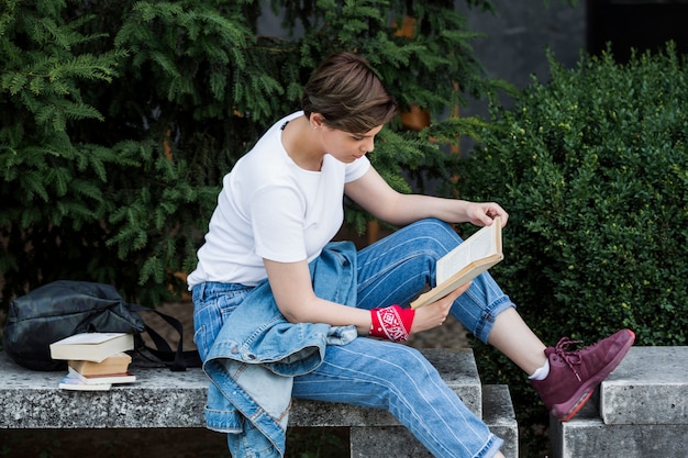 Libro di lettura studentessa sul parapetto del parco