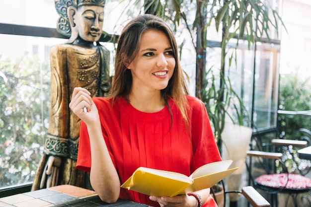 Libro felice della tenuta della giovane donna in ristorante