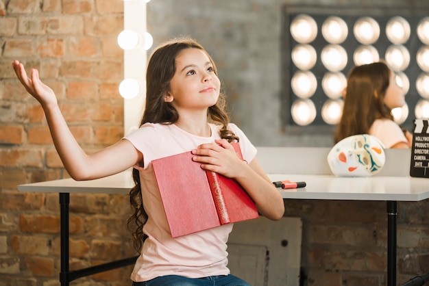 Libro sveglio della tenuta della ragazza che prova al backstage