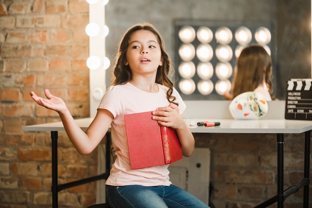 Libro sveglio della tenuta della ragazza che prova al backstage