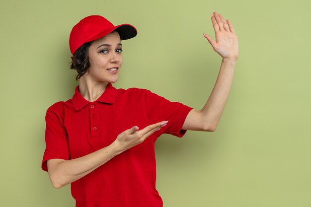 Lieta giovane graziosa donna delle consegne che indica la sua mano