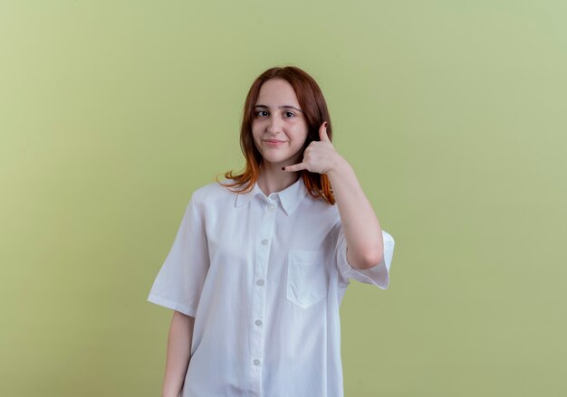 Lieta giovane ragazza rossa che mostra il gesto di chiamata telefonica isolato su verde oliva con lo spazio della copia