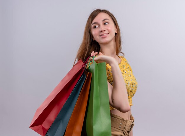 Lieta ragazza con i sacchetti di carta sulla spalla guardando il lato sinistro