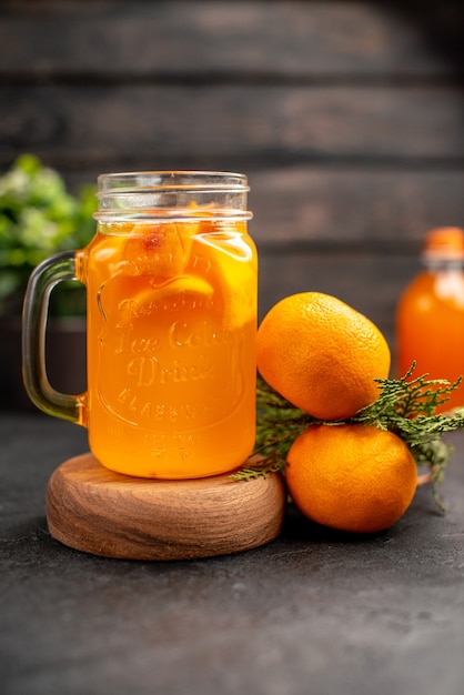 Limonata all'arancia vista frontale in vetro su tavola di legno arance su superficie marrone isolata