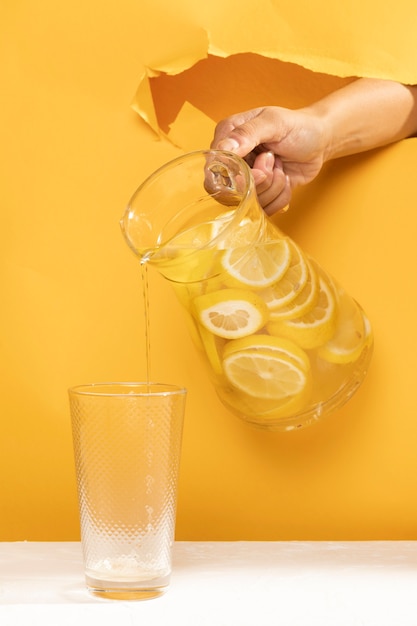 Limonata di versamento della mano del primo piano in un vetro