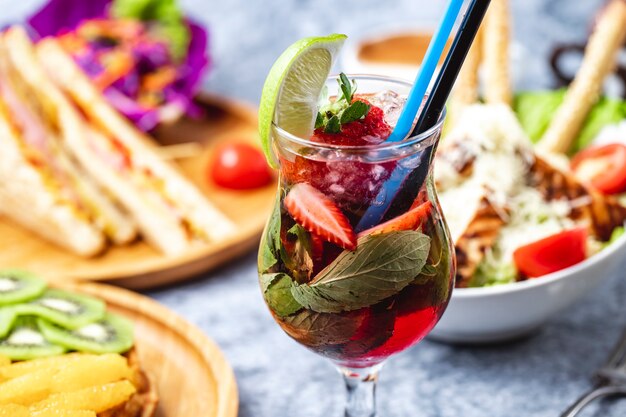 Limonata fatta in casa vista laterale con fetta di fragola di limone e menta nel bicchiere