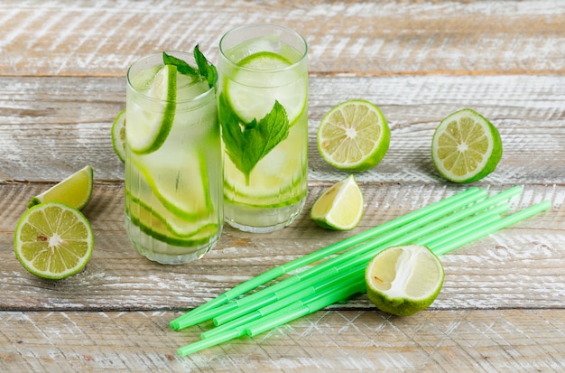 Limonata in bicchieri con limone, basilico, cannucce veduta dall'alto su un legno