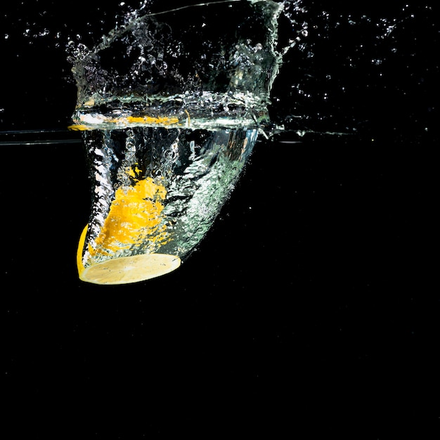 Limone giallo che cade nella spruzzata dell&#39;acqua