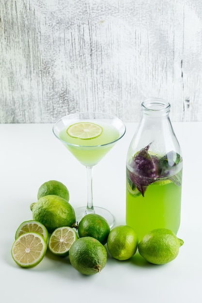 Limoni con limonata, vista dell'angolo alto delle foglie del basilico su bianco e grungy