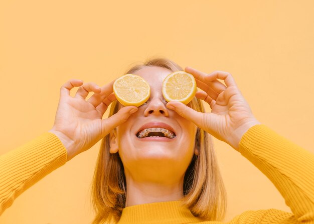 Limoni della holding della donna davanti agli occhi in una scena gialla