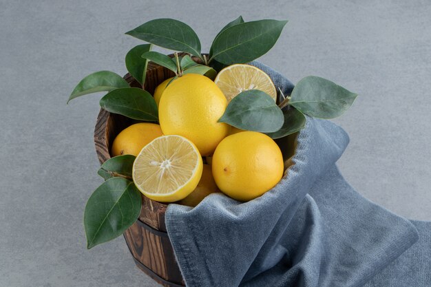 Limoni e foglie ammucchiati in un secchio su marmo