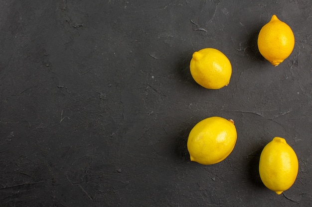 Limoni freschi di vista superiore allineati sullo spazio libero della frutta gialla degli agrumi della tavola scura per testo