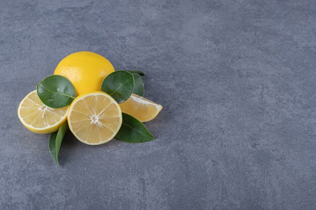 Limoni freschi interi o tagliati a metà su sfondo grigio.