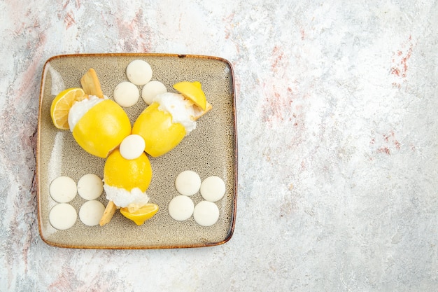 Limoni ghiacciati di vista superiore con le caramelle bianche sul succo del cocktail della bevanda della frutta della tavola bianca