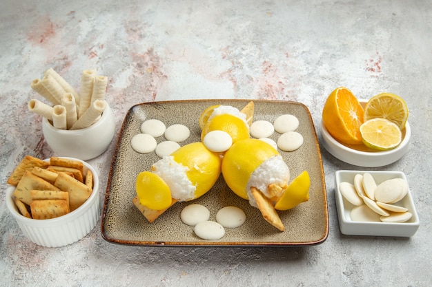 Limoni ghiacciati vista frontale con caramelle e biscotti sulla bevanda di frutta cocktail succo da tavola bianco
