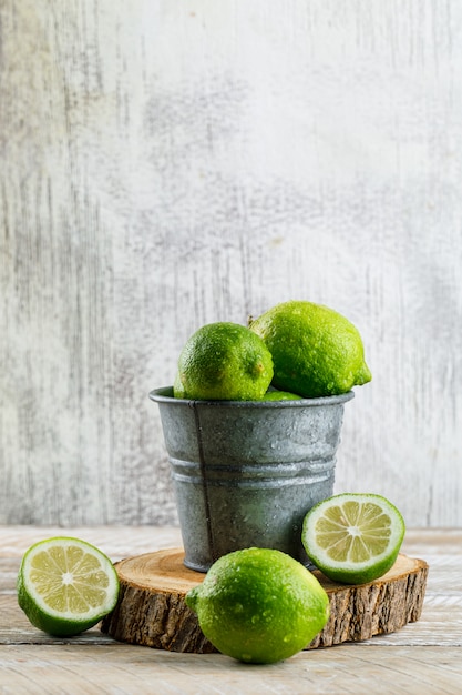 Limoni in un mini secchio con la vista laterale del tagliere su di legno e grungy