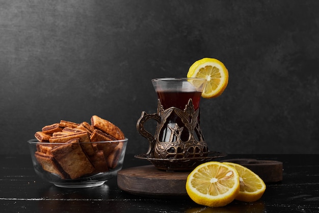 Limoni isolati su una tavola di legno con cracker e un bicchiere di tè.