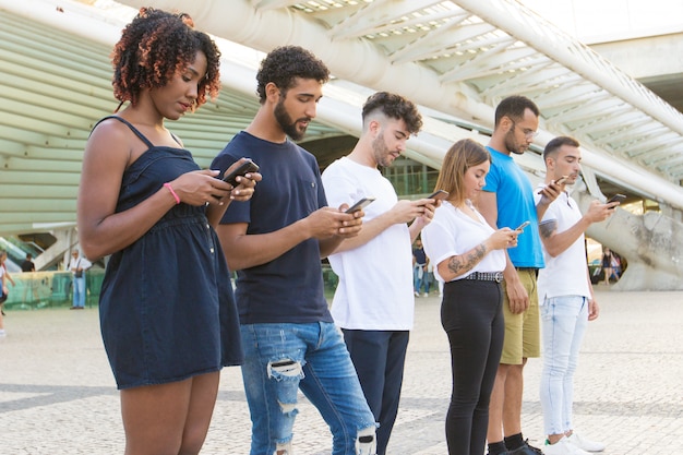 Linea di persone che navigano in Internet su smartphone all'esterno