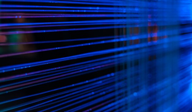 Linee di luce blu e punti da cavi in fibra ottica su uno sfondo scuro, idea di comunicazioni del computer, messa a fuoco selettiva, sfocatura, sfondo scuro