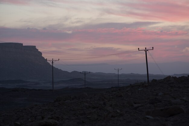 Linee elettriche aeree nella valle sotto il cielo nuvoloso al tramonto