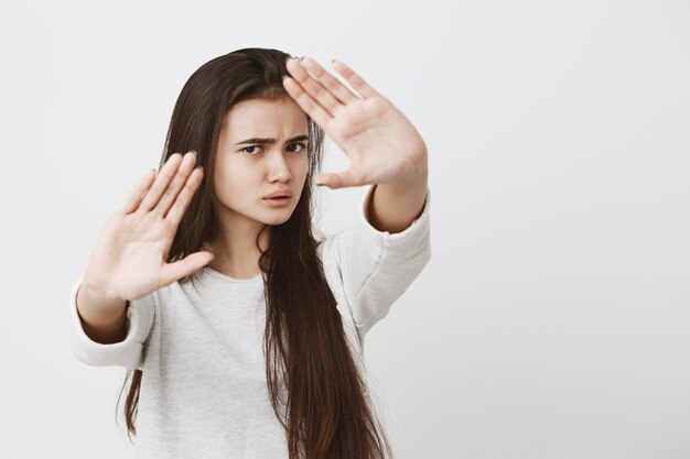 Linguaggio del corpo. Stressata bella donna adolescente arrabbiata che tiene le mani in gesto di arresto, cercando di difendersi come se stesse dicendo: Stai lontano da me