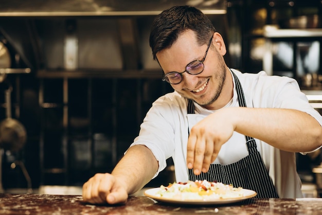 Lo chef dell'uomo in cucina spruzza la salsa di cavolo con il melograno