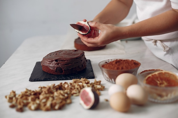 Lo chef in abiti bianchi prepara una torta al cioccolato. La signora sta preparando il dessert. La donna cuoce una torta.