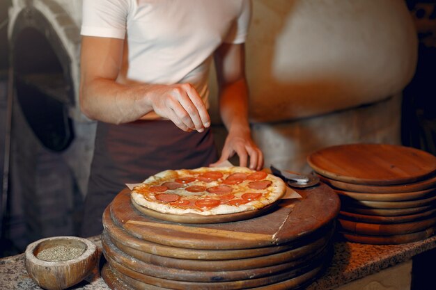 Lo chef in uniforme bianca prepara una pizzaa