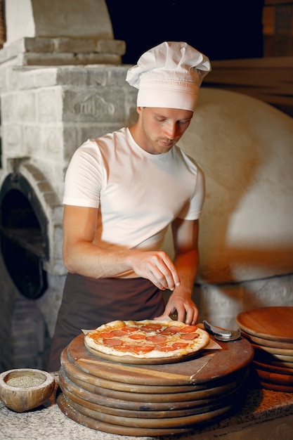 Lo chef in uniforme bianca prepara una pizzaa