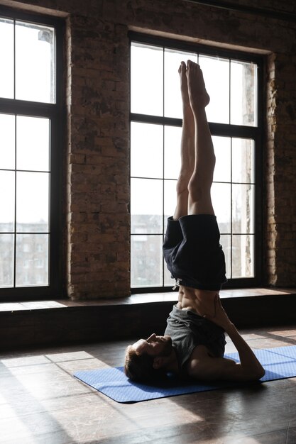 Lo sportivo forte concentrato in palestra fa esercizi sportivi di yoga.