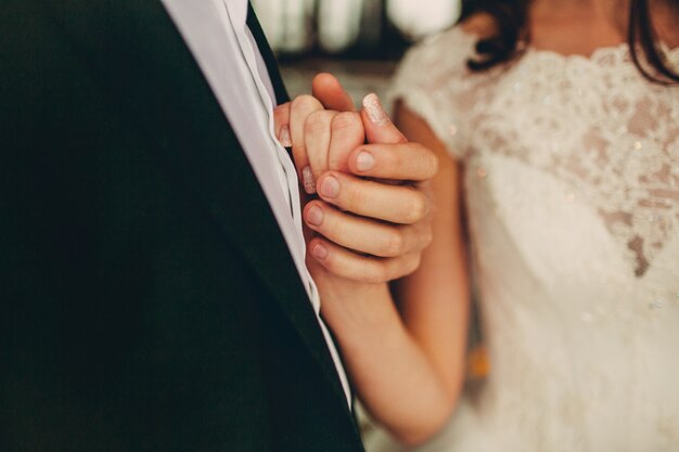 Lo sposo tiene la mano della sposa vicino al suo cuore