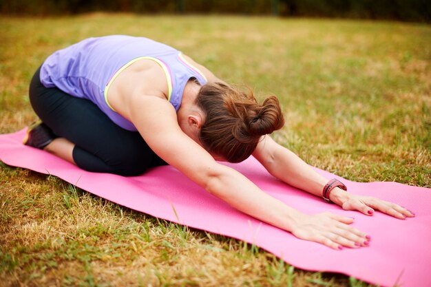 Lo stretching è molto importante dopo gli esercizi fisici. Giovane donna che fa yoga all'esterno.