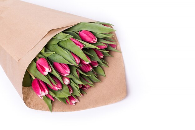 Lotto di tulipani rossi in carta marrone isolato su bianco