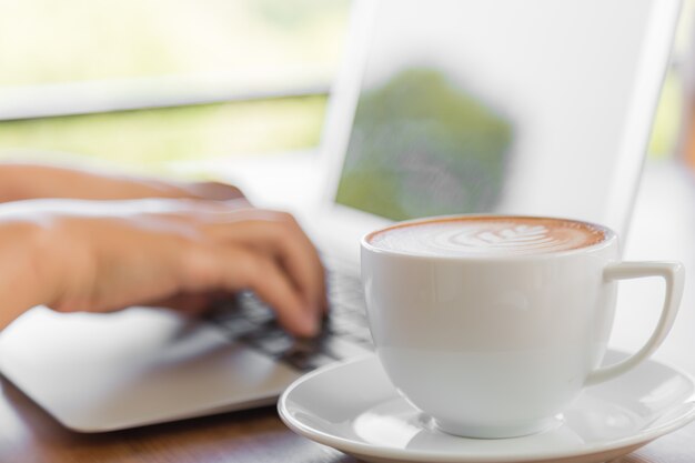Lperson lavorando su un computer portatile con una tazza di caffè accanto