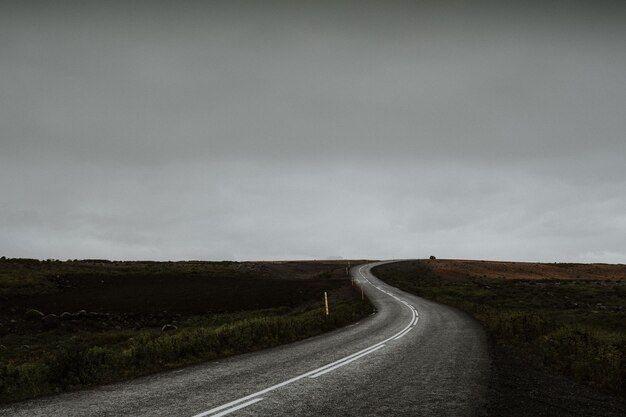 Lunga strada sinuosa nel mezzo di un campo verde in Islanda