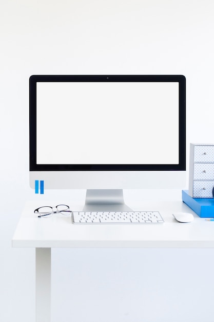 Luogo di lavoro con tastiera vicino a monitor, occhiali e mouse del computer
