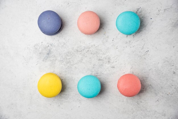 Macarons di mandorle colorati su superficie bianca. Lay piatto.