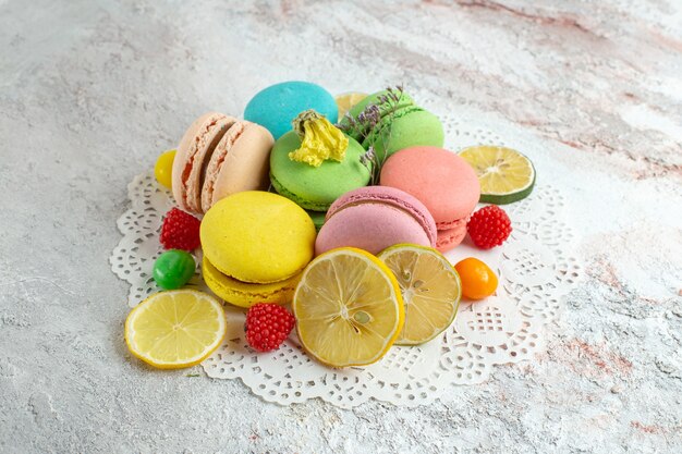 Macarons francesi di vista frontale con fette di limone su uno spazio bianco chiaro