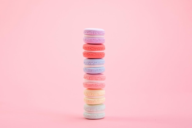 Macarons francesi dolci e colorati impilati uno sopra l'altro su sfondo rosa