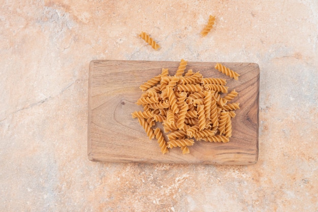 Maccheroni a spirale crudi di Brown sul bordo di legno.