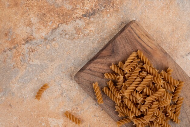 Maccheroni a spirale crudi marroni su tavola di legno. Foto di alta qualità