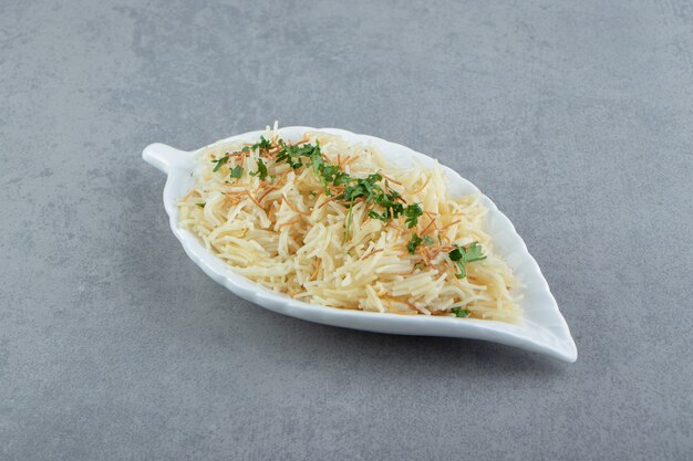 Maccheroni al prezzemolo tritato su piatto a foglia