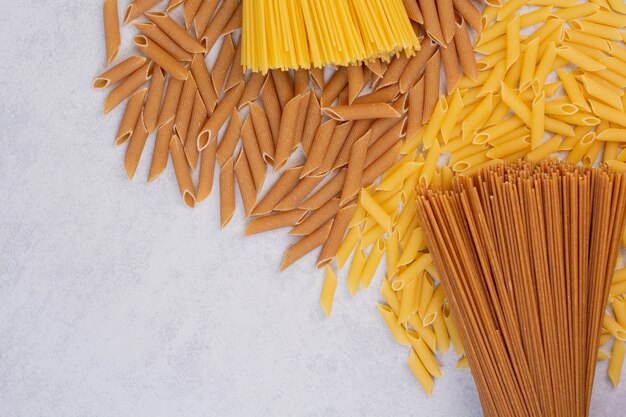 Maccheroni crudi con pasta fresca cruda su uno spazio bianco.