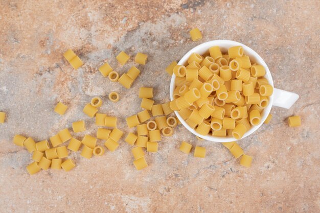 Maccheroni deliziosi crudi sulla tazza bianca.