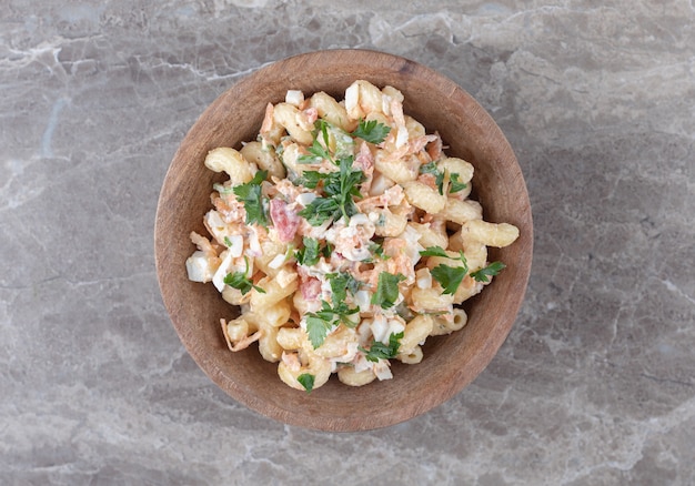 Maccheroni saporiti con insalata mista in ciotola di legno.