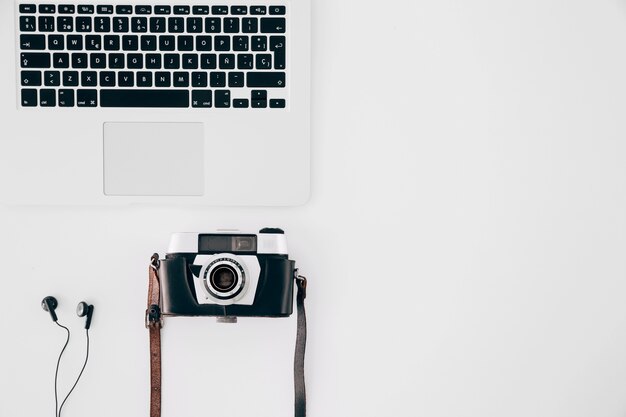 Macchina fotografica d&#39;epoca; auricolare e un computer portatile aperto su sfondo bianco