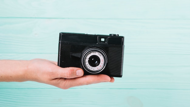 Macchina fotografica della holding della mano davanti a priorità bassa blu