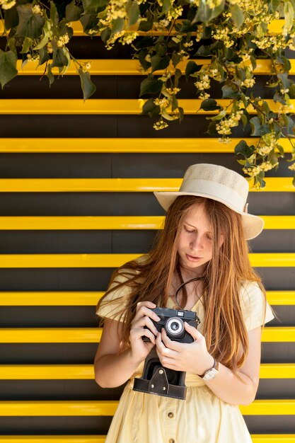 Macchina fotografica della tenuta della ragazza di vista frontale