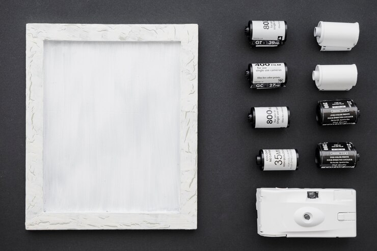 Foto gratuito macchina fotografica e film vicino alla cornice bianca